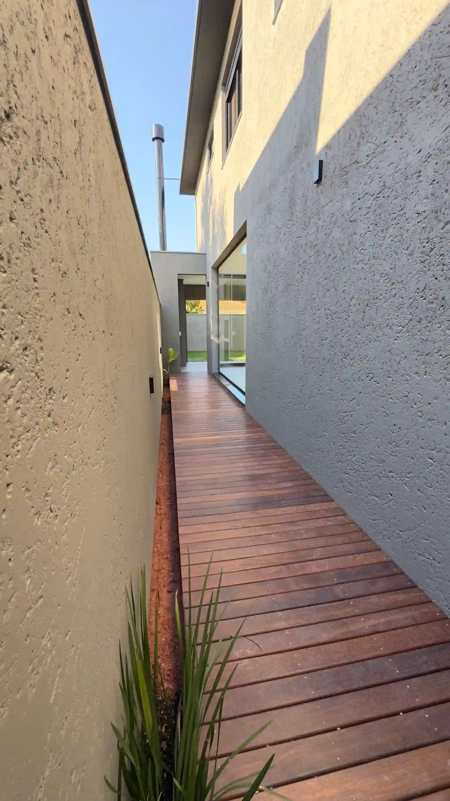 Timber side walkway through coastal planting beside a completed Florianópolis home
