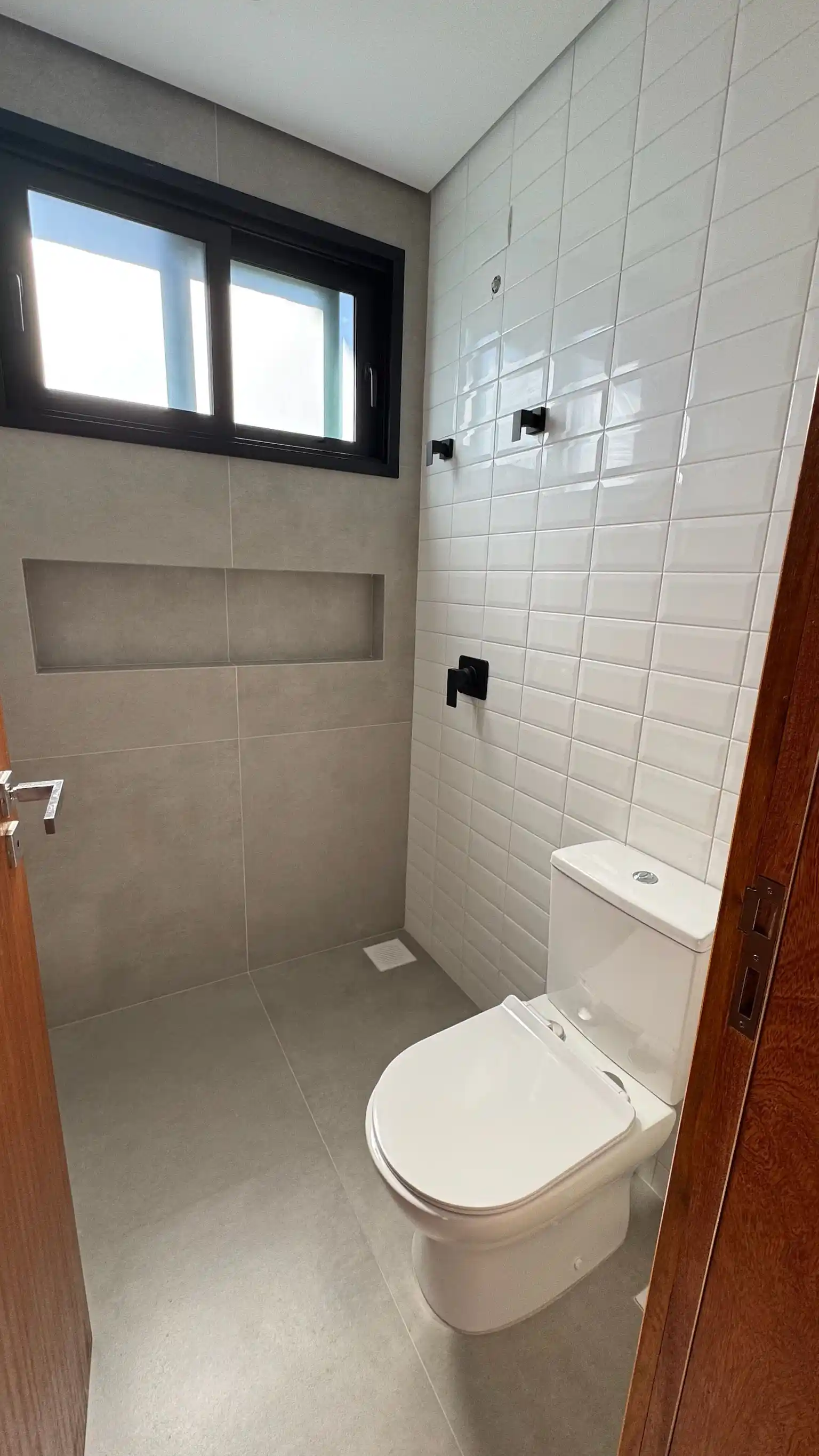 Bathroom interior with a walk-in shower behind clear glass and dark metal fittings