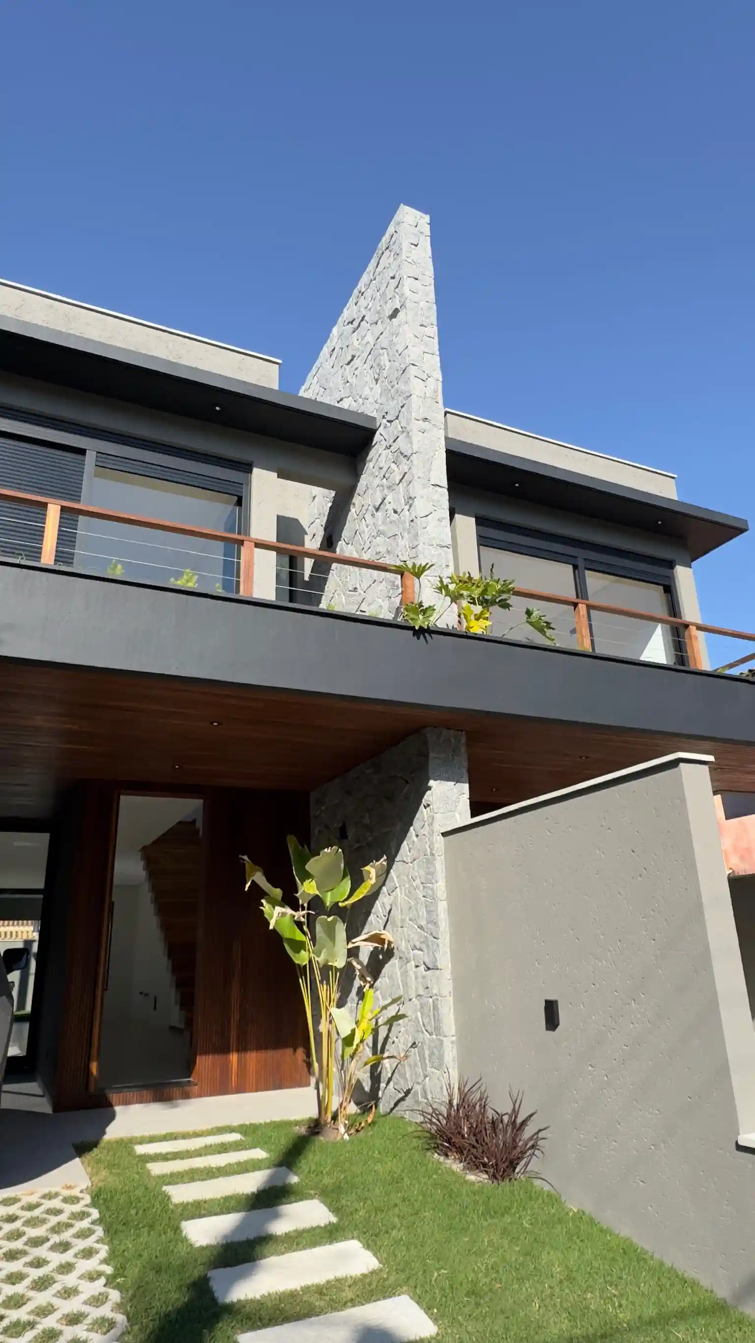 Casas Açores exterior with timber terrace, stone chimney and planted garden