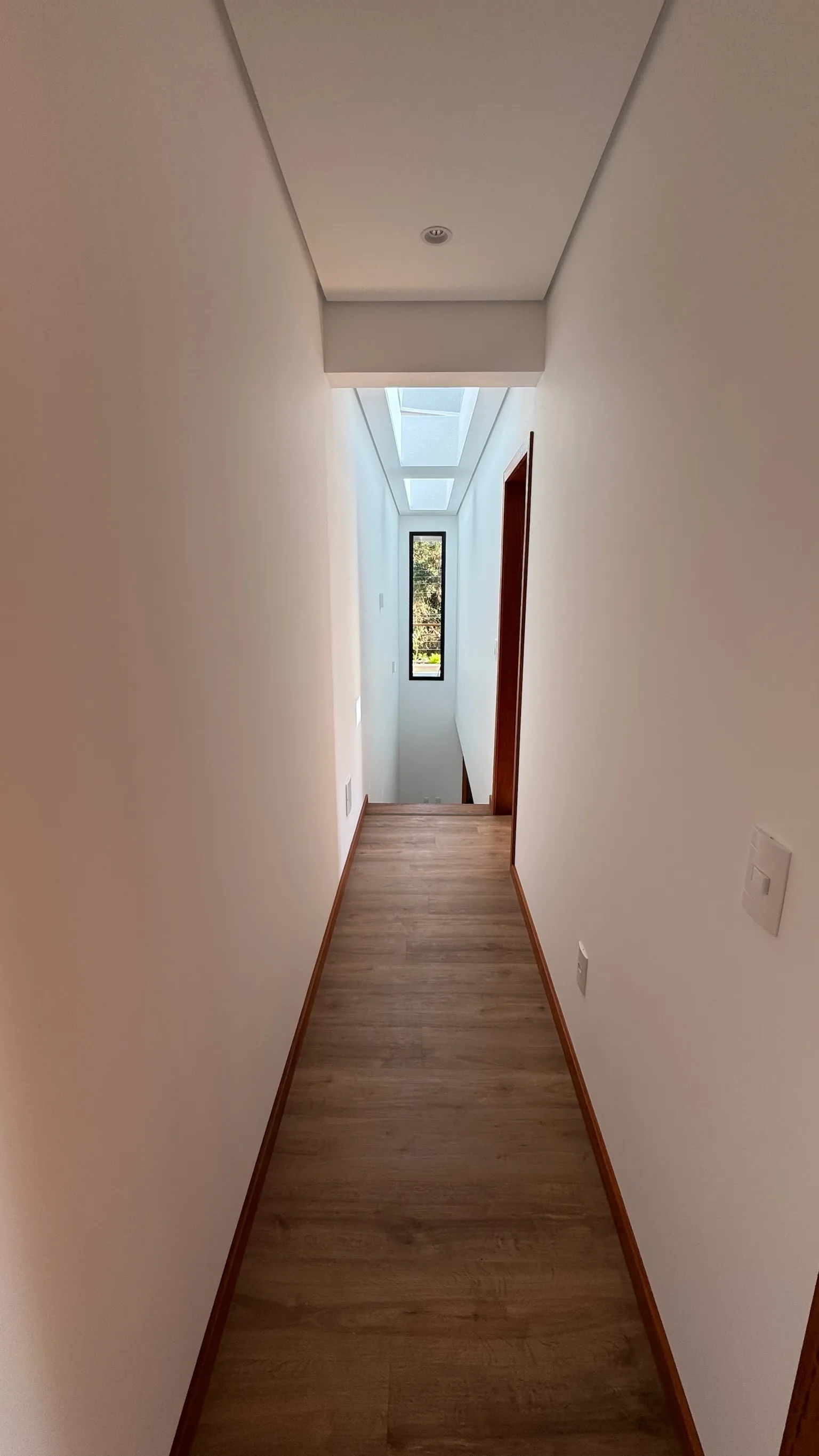 Upper corridor with a sequence of rectangular rooflights above the timber-toned floor