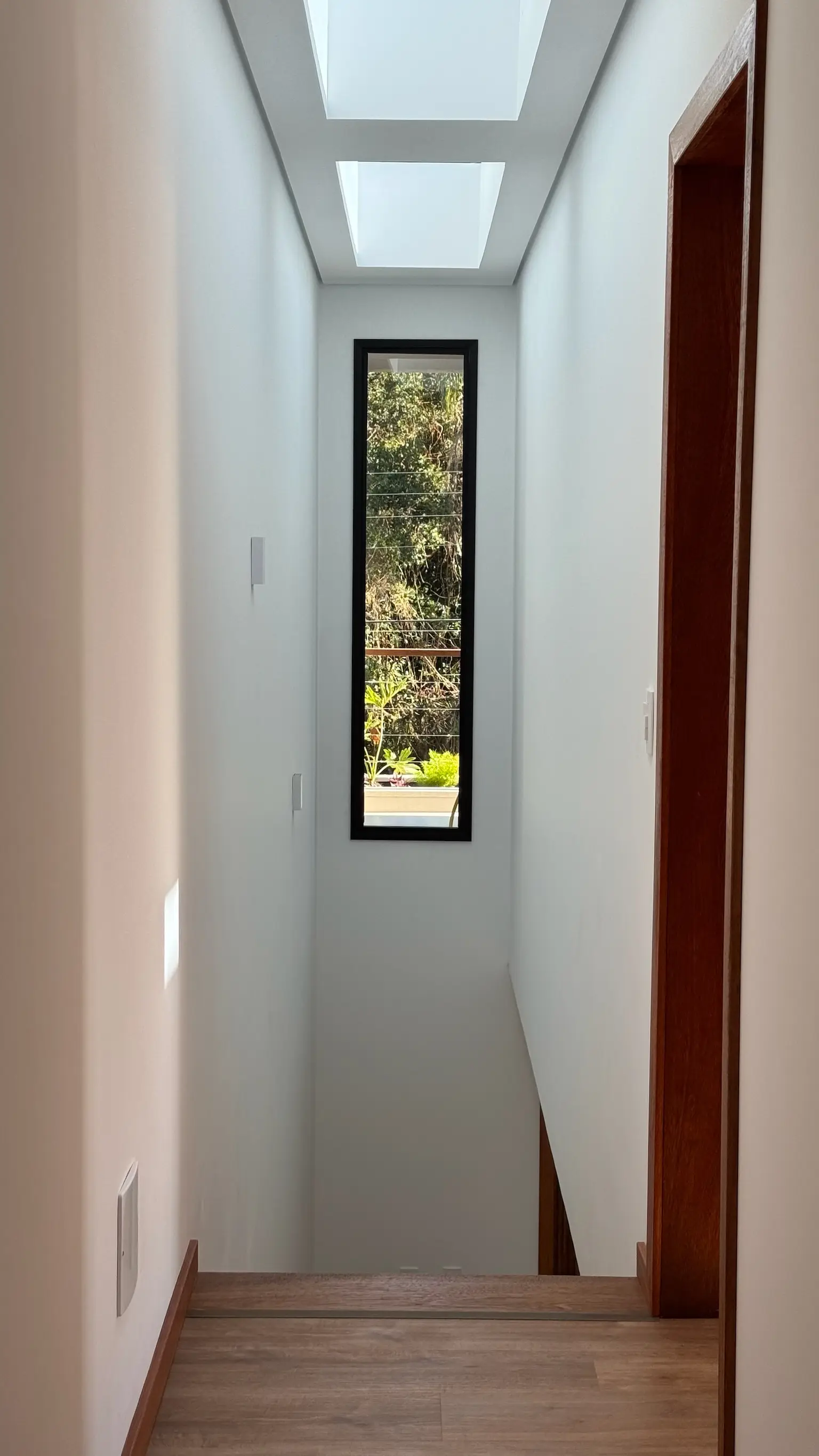 Corredor com janela alta e estreita com vista para o jardim