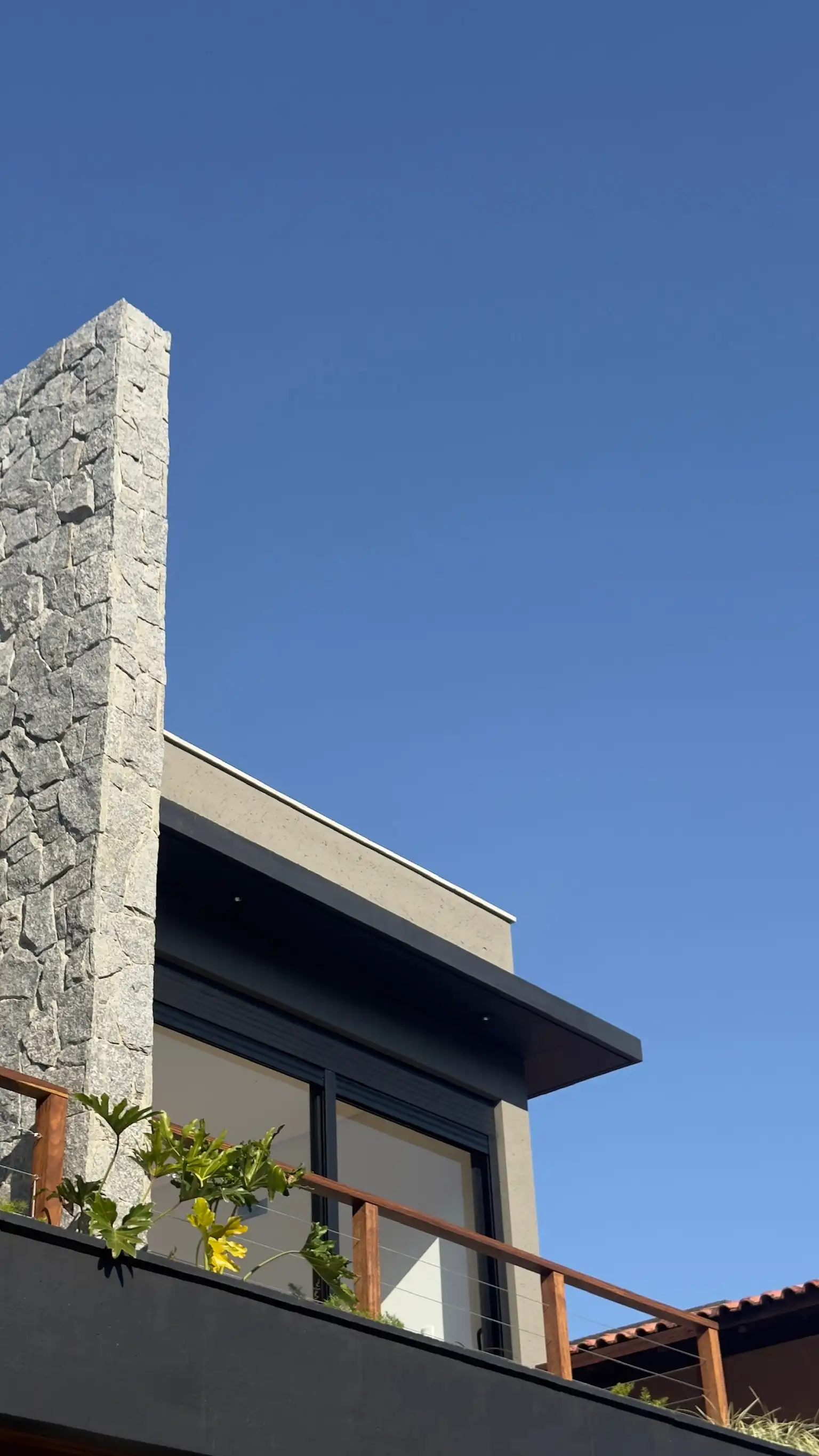 Close view of the pale stone chimney rising through the clean-lined upper facade