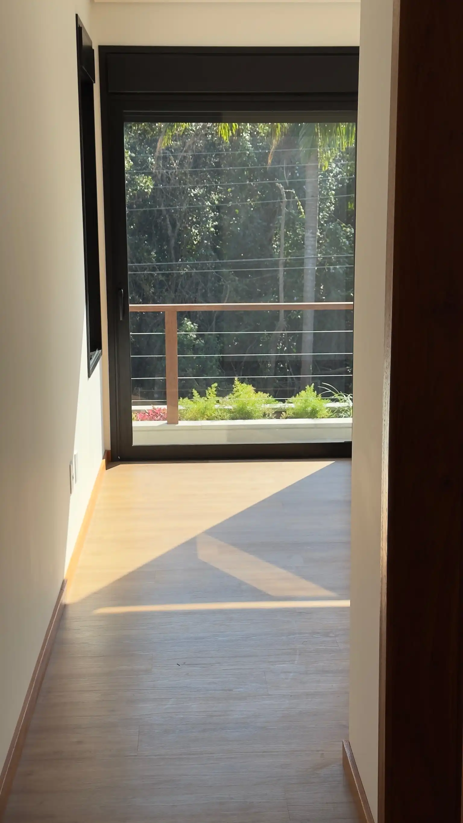 Principal bedroom interior with timber-toned floor and full-height glazed opening