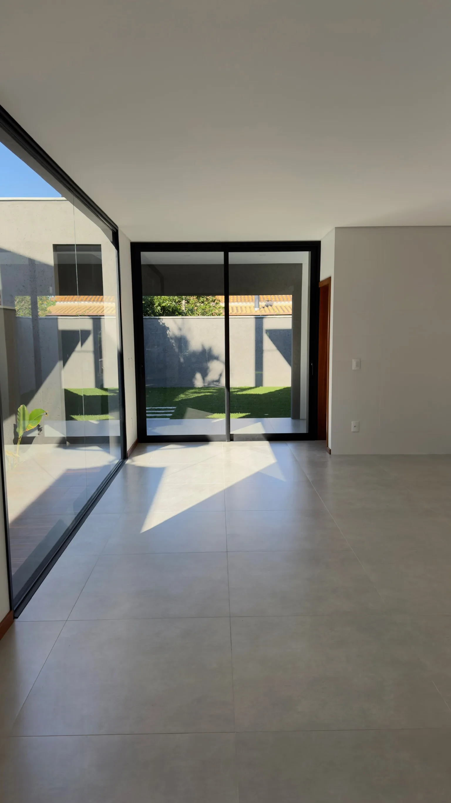 Living space with broad sliding glass doors opening towards the internal planted patio