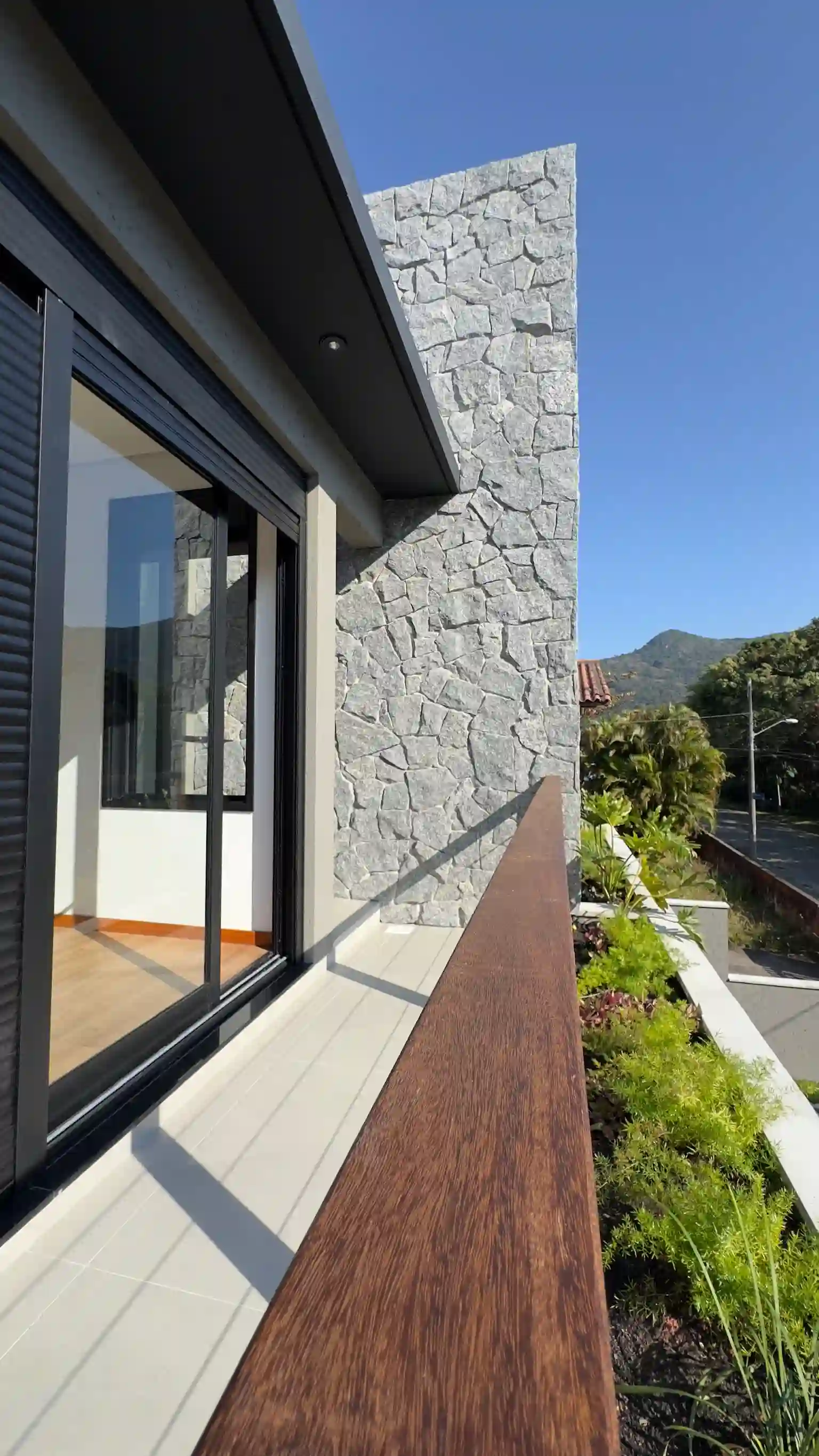 Side view along the upper balcony with timber rail and surrounding green vegetation