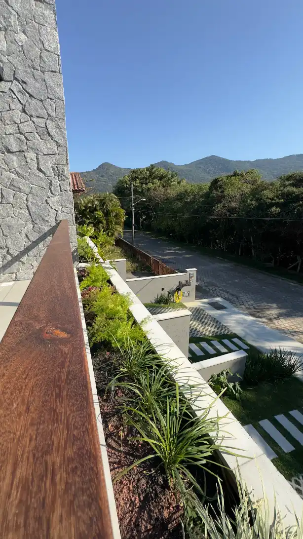 Timber balcony overlooking a quiet residential street and forested hills in southern Florianópolis